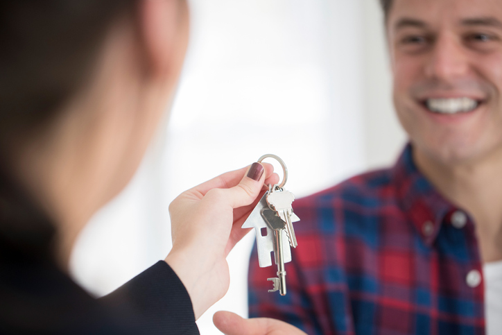 mężczyzna odbierający klucze do nowego domu od kobiety agenta nieruchomości